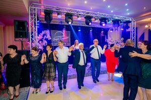 Guests perform synchronized dance moves at an elegant event venue with blue and purple lighting.