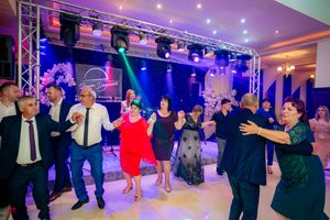 Energetic group dancing at an indoor event with professional lighting and sound equipment setup.