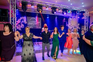 Guests performing a synchronized line dance at an elegant event with blue and purple lighting effects.