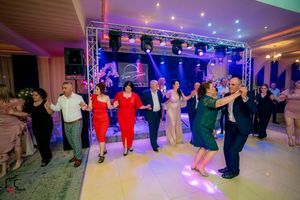 People dancing together in formal attire at a party with professional lighting and sound setup.