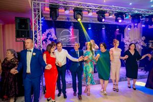 Festive line dance with participants in colorful formal attire under professional stage lighting.