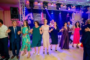 Celebration with guests in colorful formal wear dancing under professional stage lighting.