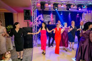 Partygoers in formal attire dance in formation at an elegantly lit indoor venue.