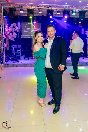 Couples dancing together at an elegant ballroom event with colorful purple and blue lighting effects.