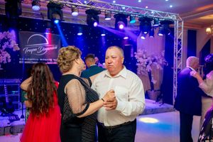 Couples ballroom dancing at a formal event with dramatic blue lighting and stage effects.