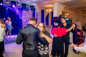 Elegant ballroom dance party with multiple couples dancing under dramatic purple lighting.
