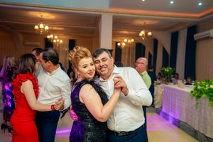 Formal dance event in an elegant venue with chandeliers and atmospheric lighting.