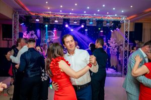 Social dance event in a grand ballroom with couples dancing under colorful lighting effects.