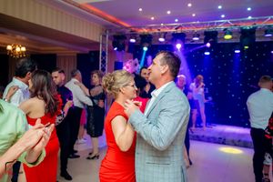 Ballroom dance celebration with multiple couples dancing under dramatic stage lighting.