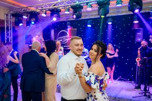 Social dancers enjoying an elegant evening event under dramatic purple stage lighting.