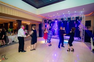 Wide view of a ballroom dance event showing multiple couples dancing under ambient lighting.
