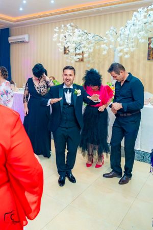 Group line dancing in an elegant ballroom with striped wallpaper and overhead lighting.