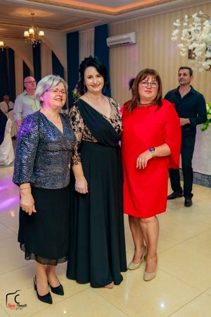 Party guests in formal attire dancing together in a festively decorated ballroom.