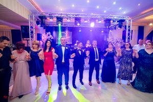 Panoramic shot of ballroom dancers under purple mood lighting and disco effects.