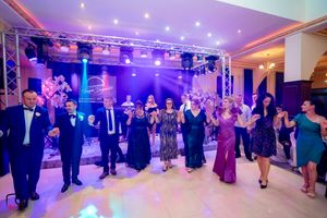 Large group of dancers performing synchronized moves in an illuminated ballroom setting.
