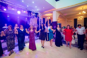 Wide angle view of a formal dance event with purple ambient lighting and chandeliers.