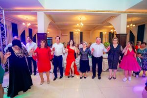 Panoramic view of dancers lined up across a elegant ballroom floor with mood lighting.