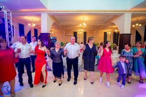 Guests dancing in a line at an elegant reception venue with purple and blue lighting.