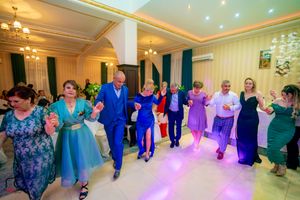 Guests in formal attire dancing together in a line at a wedding reception.