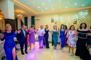 Celebration attendees in blue and purple dresses dancing in formation at an elegant venue.