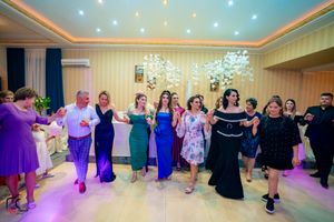 Group dance at an elegant reception with guests wearing colorful formal attire.