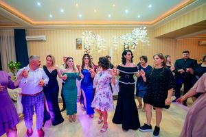 Party guests performing synchronized dance moves under decorative ceiling lights.
