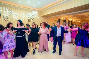 Festive group dance at an elegant venue with guests in colorful formal wear.