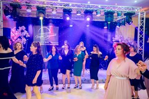 Wedding party members dance in formation under dramatic purple lighting and truss lighting system.