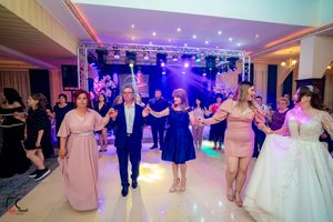 Guests perform a traditional group dance on an illuminated dance floor at an elegant wedding reception.
