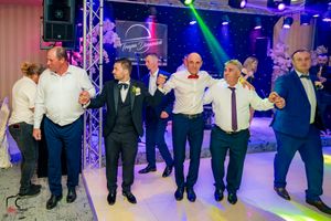 Formal wedding guests participate in a synchronized line dance at an elegant indoor venue.