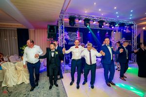 Reception guests perform coordinated dance moves in a line formation under dramatic purple lighting.