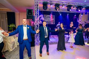 Guests engage in synchronized dancing at a formal wedding reception with dramatic lighting effects.