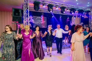 Guests in formal attire dancing together at an event with colorful lighting and stage setup.