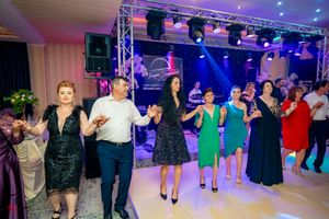 Guests performing line dance moves at an indoor event with professional stage lighting.