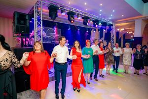 Party guests in colorful formal attire dancing in formation at an indoor celebration.