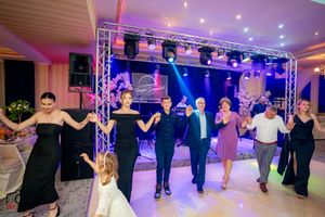 Party guests dancing in formation at a festive indoor event with professional lighting setup.