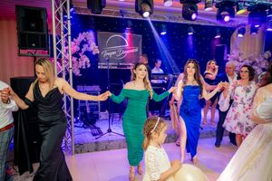 Celebration venue with dancers moving in sync under vibrant blue and purple stage lighting.