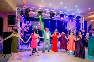 Group dance formation at a wedding reception with purple and blue lighting effects.