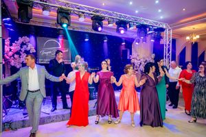 Wedding guests dancing in synchronized formation under vibrant purple and blue stage lighting.