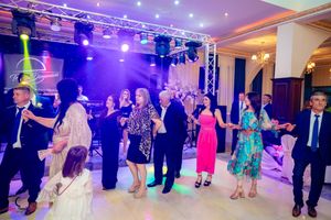 Wedding party and guests lined up for group dance under dramatic purple and blue lighting.