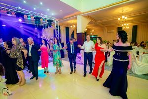 Panoramic view of wedding celebration with guests dancing in formation under mixed lighting effects.