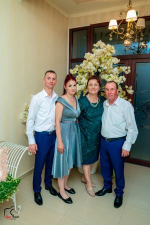 Family portrait session in a bright interior space with decorative white flowers and elegant furnishings.