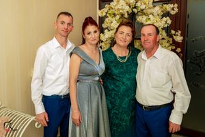 Formal group photo taken in an elegant room decorated with white floral arrangements.