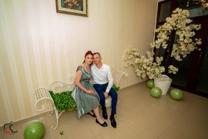 Elegant indoor photo session with decorative white bench and floral arrangements against cream walls.