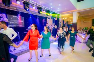 Dancers move in formation during wedding reception under colorful stage lighting and disco effects.