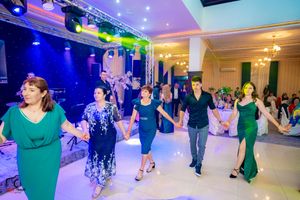 Dancers moving across a brightly lit ballroom floor with blue and purple lighting effects.
