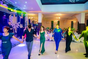 Dance floor filled with couples dancing under colorful stage lighting at an indoor social event.