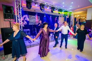 Ballroom dance event with participants moving in formation under dramatic purple and blue lights.