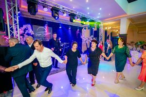 Dancers in formal attire performing synchronized movements on a professionally lit dance floor.