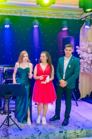 Dance showcase with performers in formal attire under vibrant green and blue stage lights.